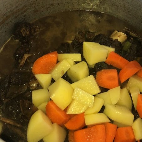 adding chopped potatoes and carrots
